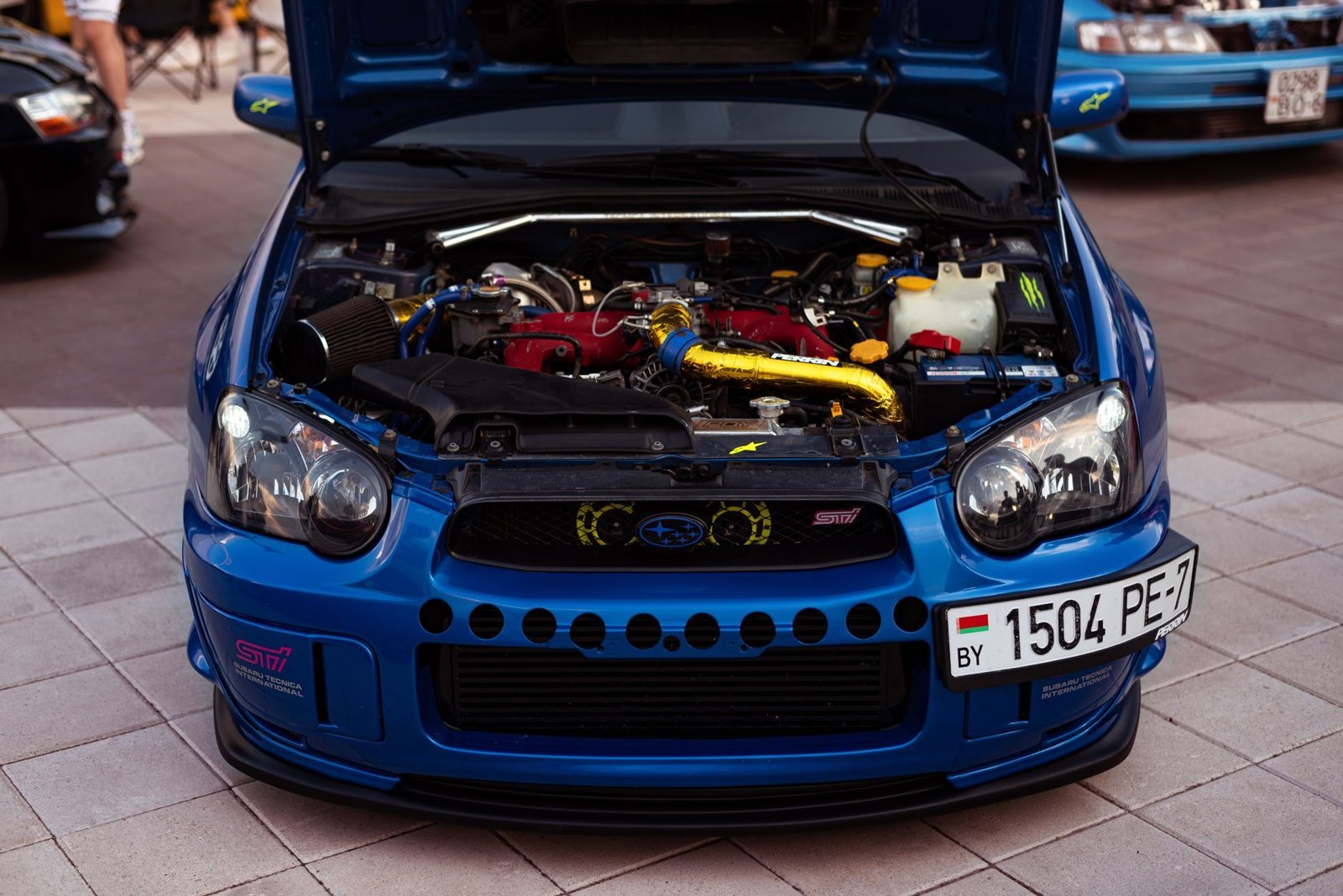 Blue Subaru Impreza STI with the bonnet raised, showing the EJ boxer engine bay