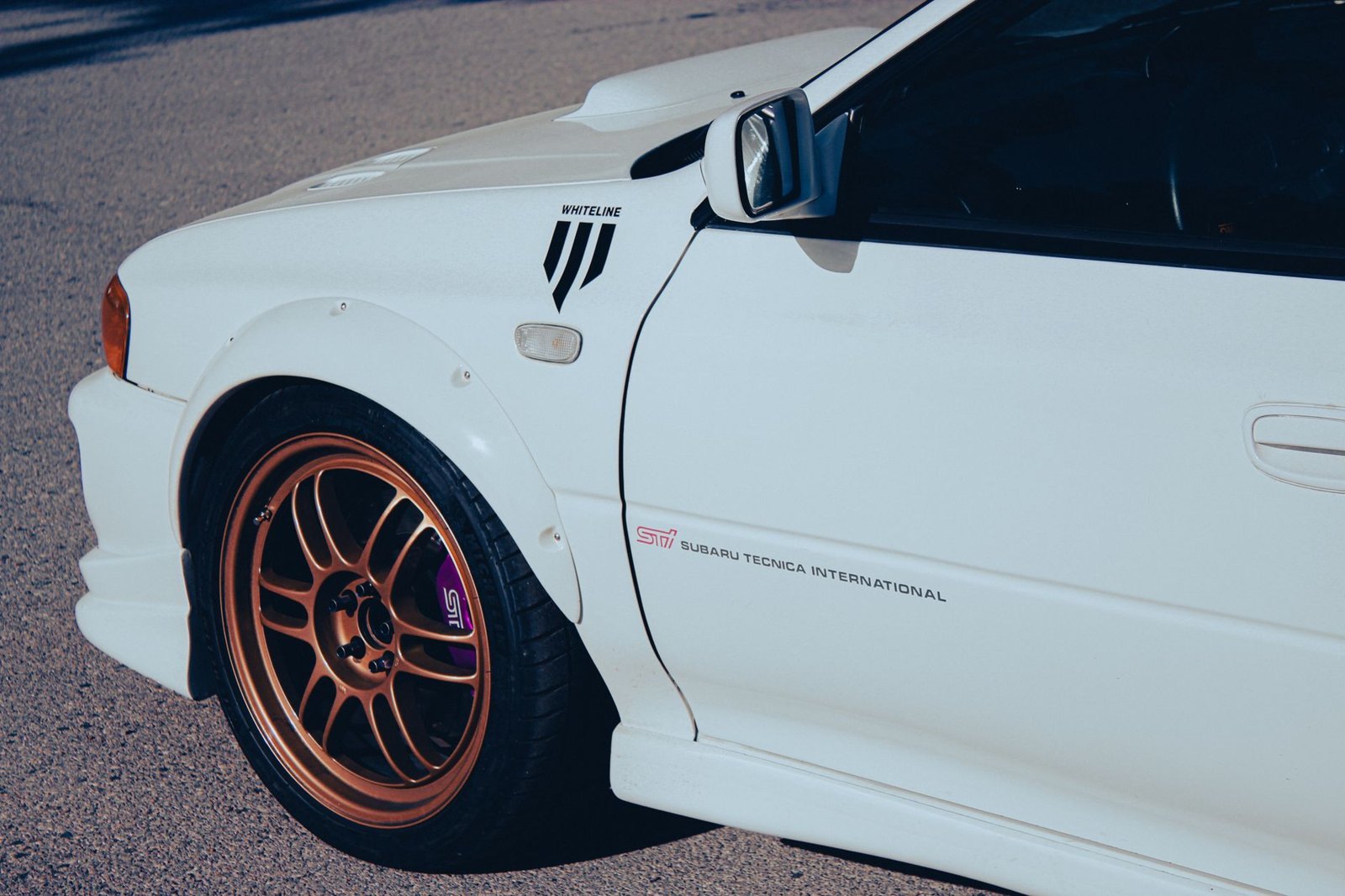 Detailed close-up of a modified Subaru sports car featuring distinctive bronze wheels and body decals.