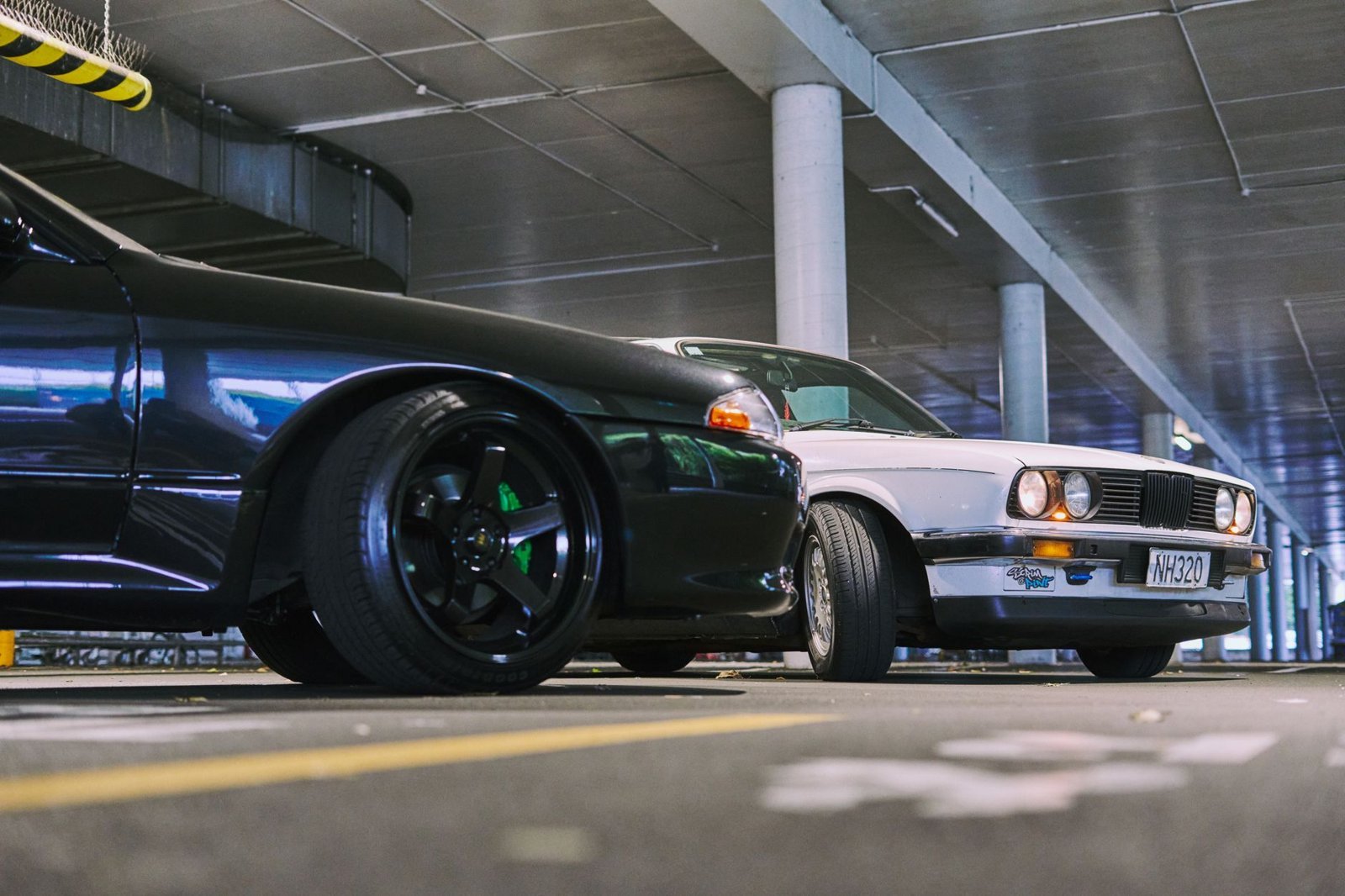 Two modified cars captured in a stylish parking garage in Auckland, New Zealand.