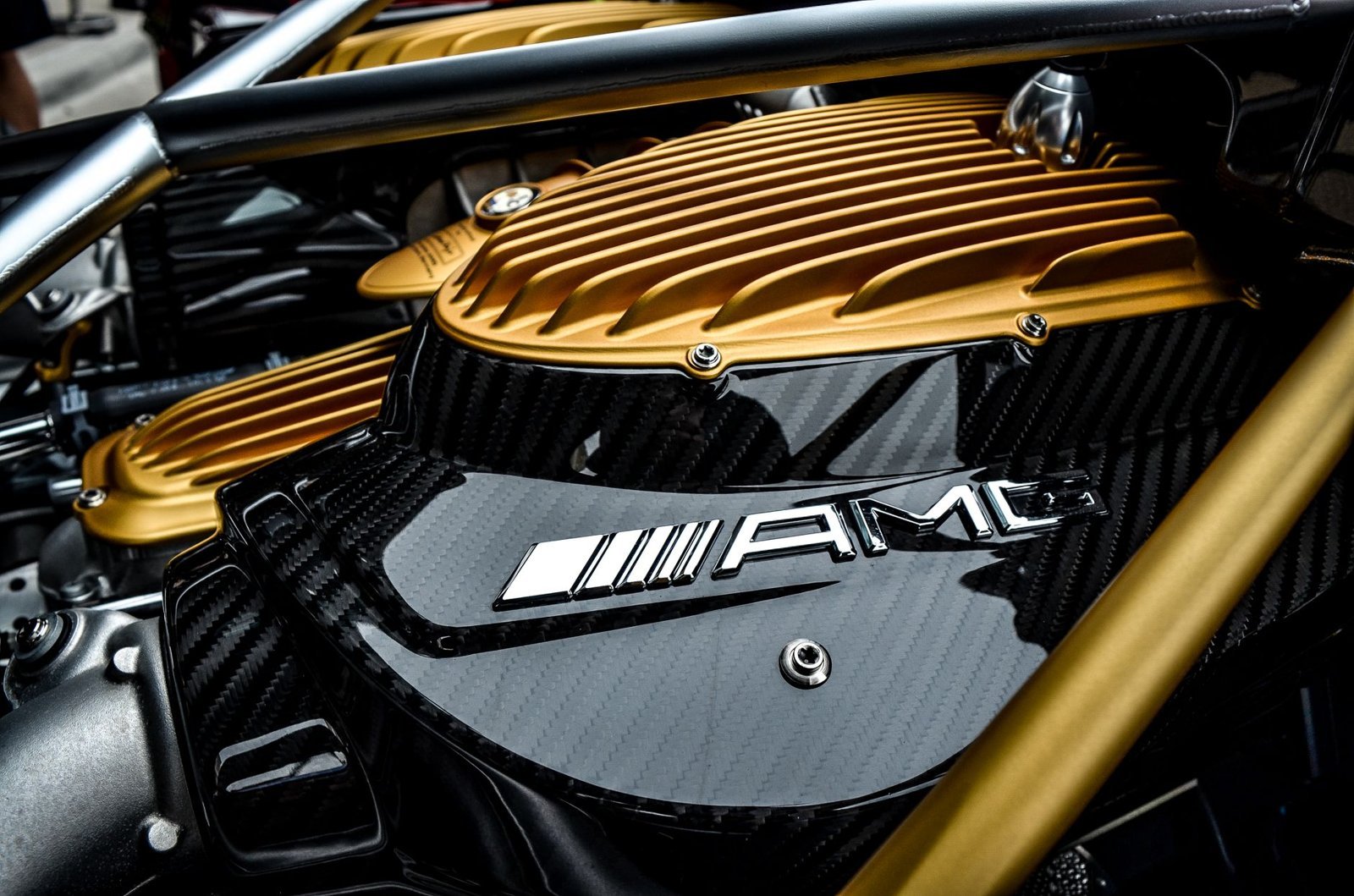 Close-up of a luxury car's engine featuring carbon fiber and gold accents, showcasing high-end design.