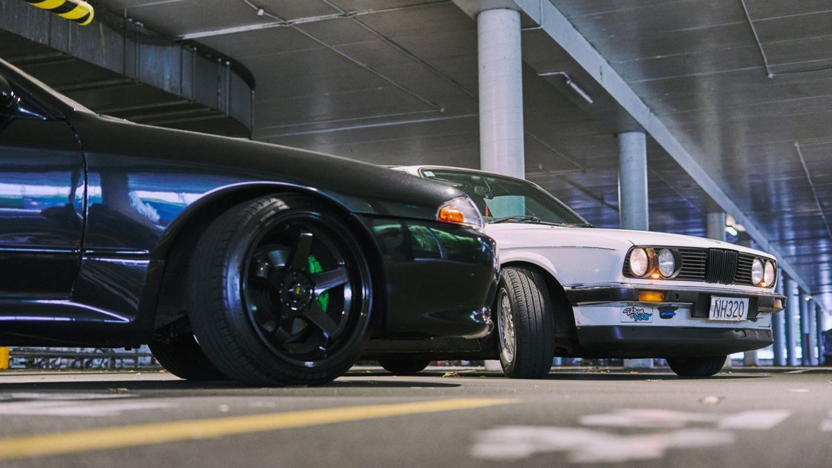 Two modified cars captured in a stylish parking garage in Auckland, New Zealand.